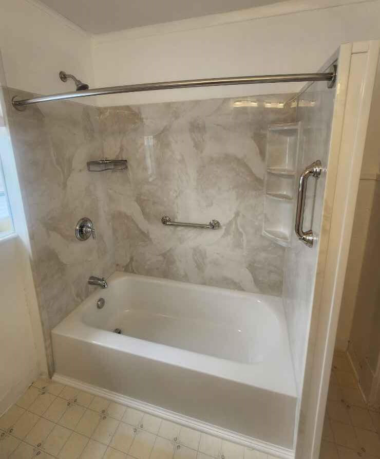 whit tub with patterned wall surround, chrome fixtures and accessories.